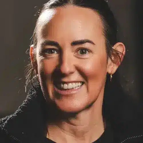 Portrait of a smiling woman with dark hair pulled back, facing the camera.